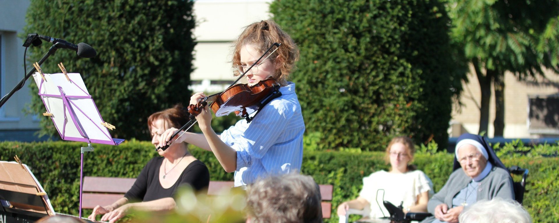 Ein Konzert im Freien: eine Junge Frau spielt Geige - eine andere Keyboard - Besucher im Hintergrund