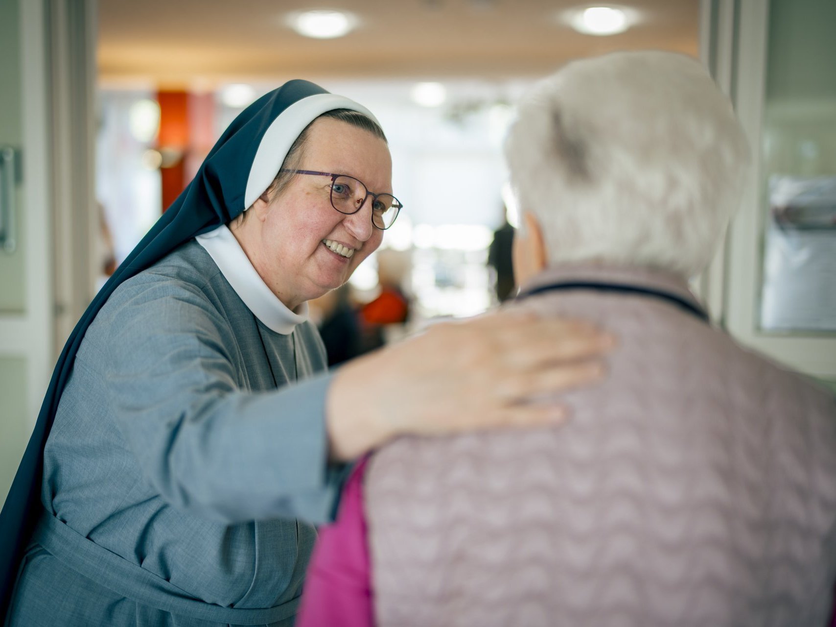 Eine Ordensschwester unterhält sich herzlich mit einer Seniorin.
