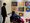Ein Mann steht neben einer Person im Rollstuhl. Beide betrachten gemeinsam sechs bunte, abstrakte Gemälde mit konzentrischen Kreisen an einer weißen Wand in einer Galerie.