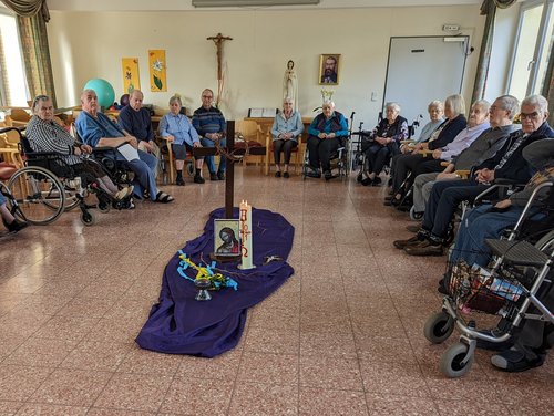 Gottesdienst oder Andacht: Frauen und Männer im Kreis um ein Kreuz und die Osterkerze