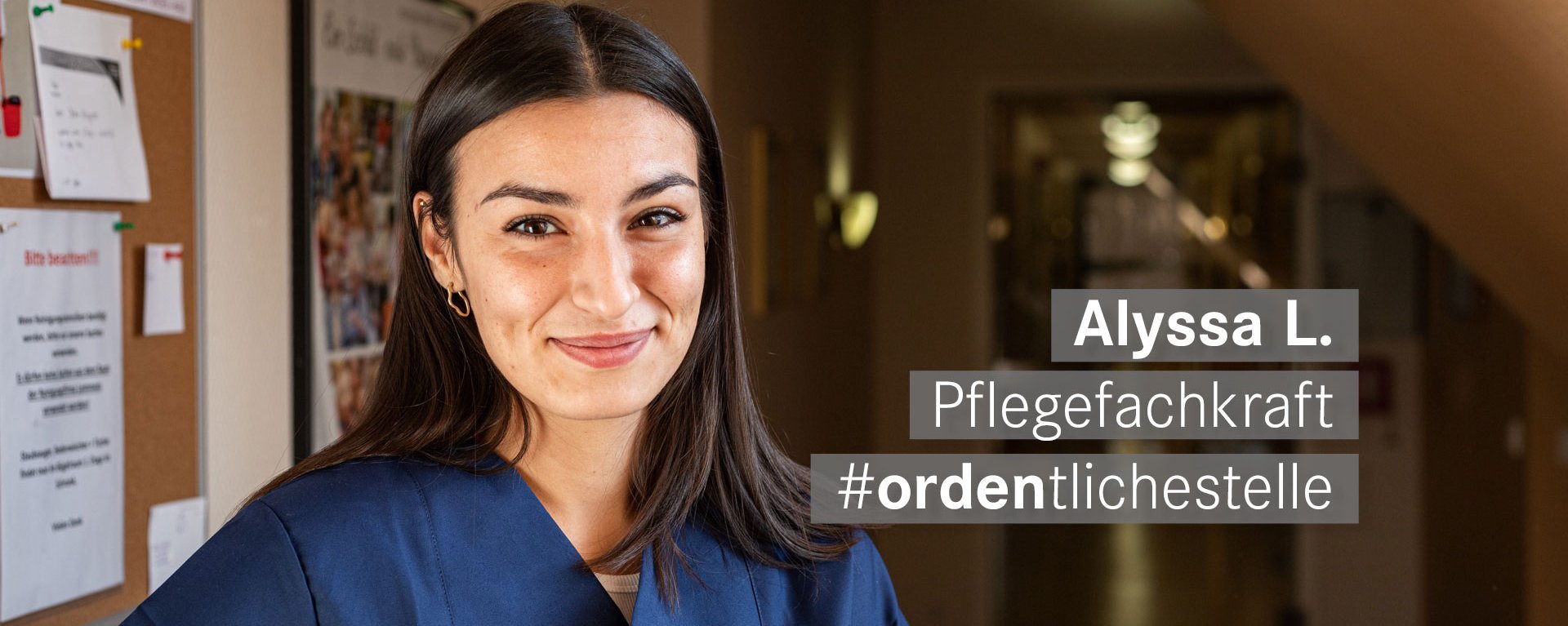 Pflegekraft mit braunen Haaren und Augen laechelt freundlich in die Kamera