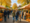 Ein belebter Herbstmarkt unter leuchtend gelben Bäumen. Menschen schlendern zwischen Marktständen mit rot-weiß gestreiften Markisen. Im Vordergrund liegen Kürbisse auf dem Kopfsteinpflaster, während eine Familie mit zwei Kindern den Weg entlanggeht.