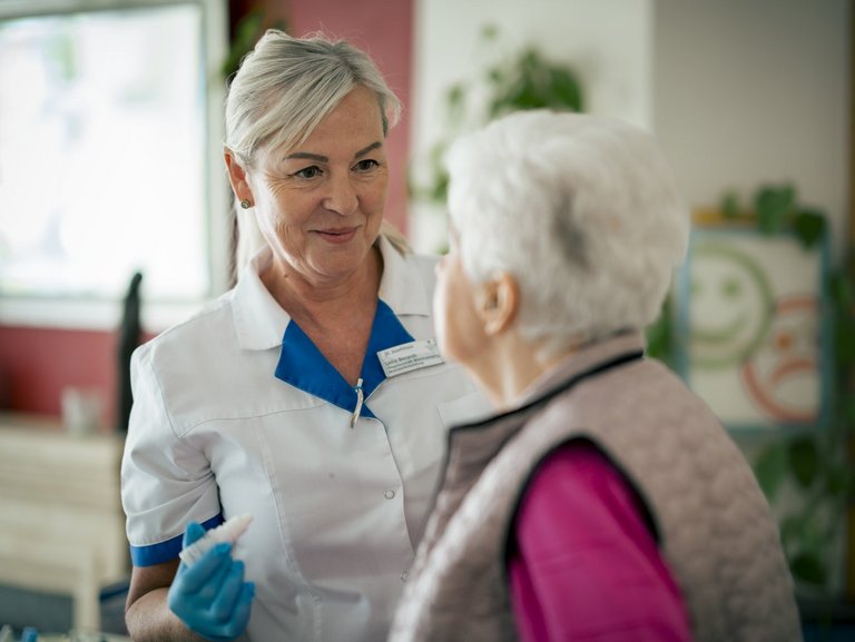 Eine Mitarbeiterin hört einer Seniorin zu, die ihr etwas erzählt.