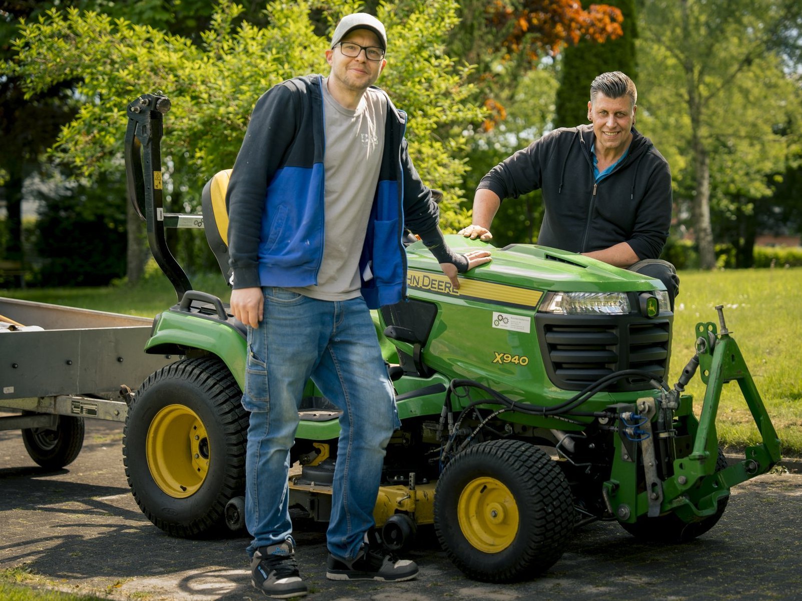 Das Hausmeister-Team lehnt stolz am Rasenmäher-Traktor der Altenhilfe-Einrichtung.
